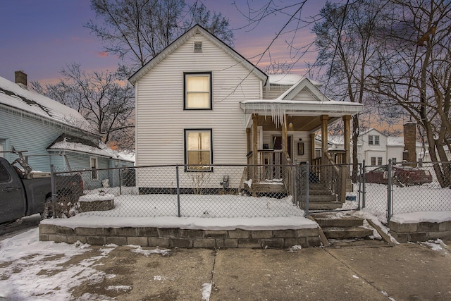 snow covered house featuring covered porch and fence