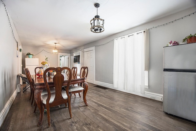dining space featuring dark wood-type flooring, baseboards, a notable chandelier, and visible vents