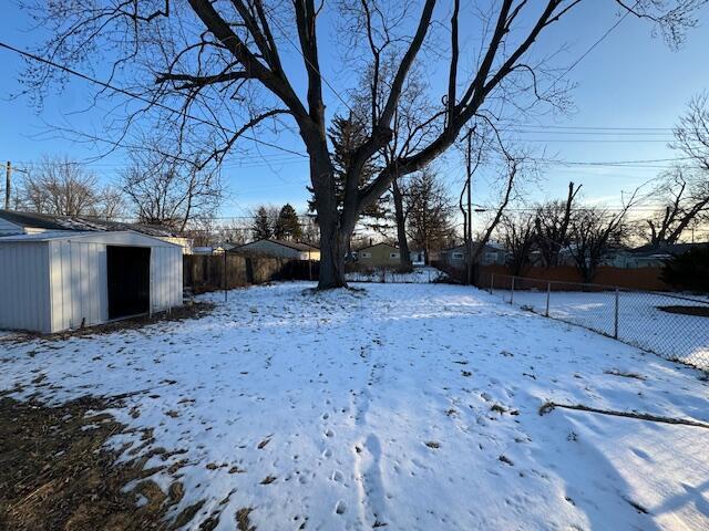 yard layered in snow with a storage shed