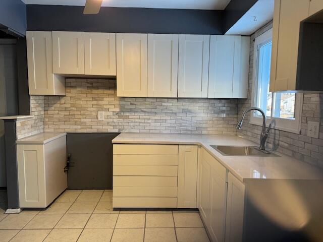 kitchen with white cabinetry, light tile patterned flooring, sink, and decorative backsplash