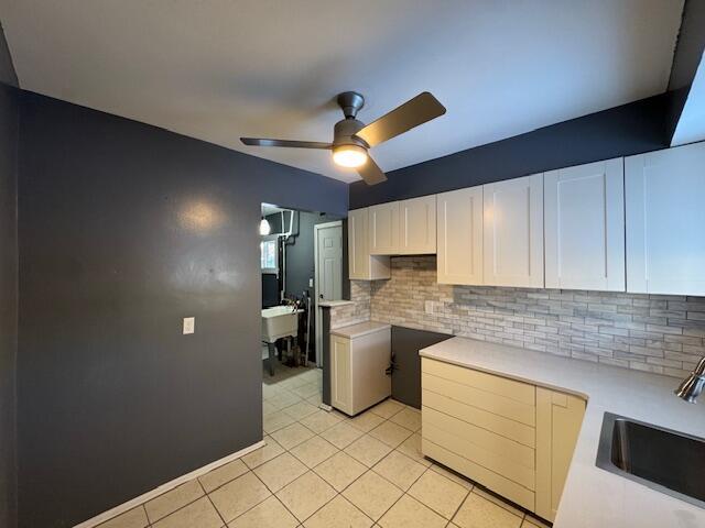 kitchen with sink, white cabinetry, light tile patterned floors, ceiling fan, and decorative backsplash