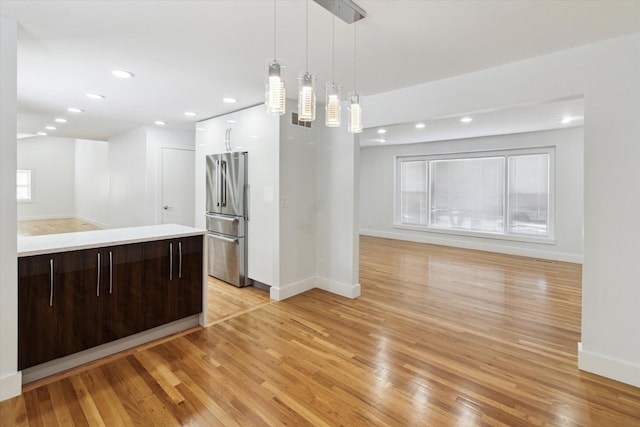 kitchen with light hardwood / wood-style floors, dark brown cabinets, stainless steel refrigerator, and decorative light fixtures