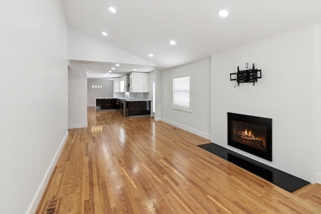 unfurnished living room with vaulted ceiling and light hardwood / wood-style floors