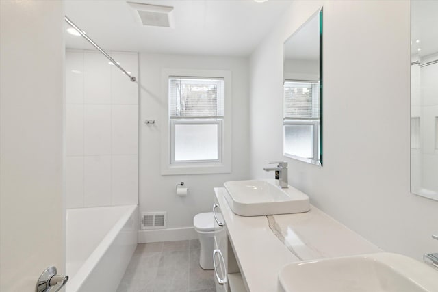 full bathroom with tiled shower / bath, vanity, and toilet