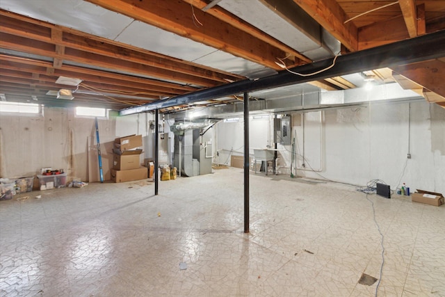 basement with electric panel, sink, heating unit, and gas water heater