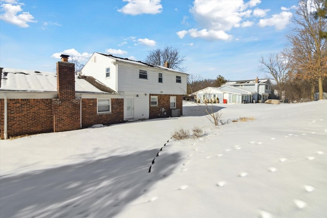 snow covered rear of property featuring central AC