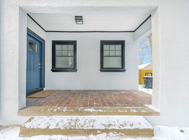 snow covered property entrance featuring a patio area