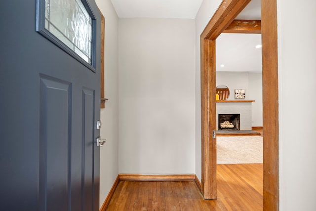 foyer entrance featuring hardwood / wood-style floors and a brick fireplace