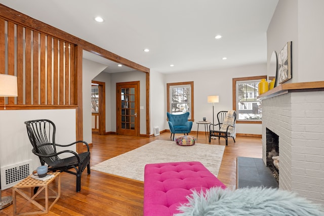 living room with a brick fireplace and light hardwood / wood-style flooring