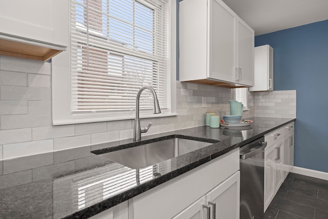 kitchen featuring sink, white cabinetry, tasteful backsplash, stainless steel dishwasher, and dark stone counters