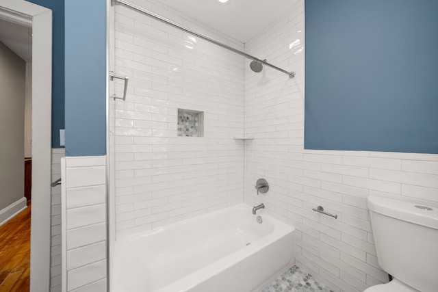 bathroom with tiled shower / bath, tile walls, and toilet