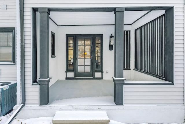 view of exterior entry with central AC unit and a porch