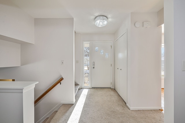 foyer with an inviting chandelier and light colored carpet