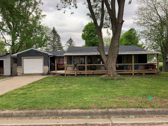 single story home featuring a garage, covered porch, and a front lawn