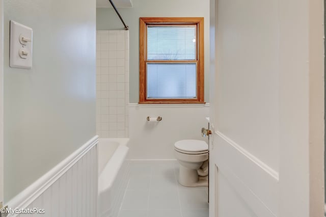 bathroom featuring tiled shower / bath combo, tile patterned floors, and toilet