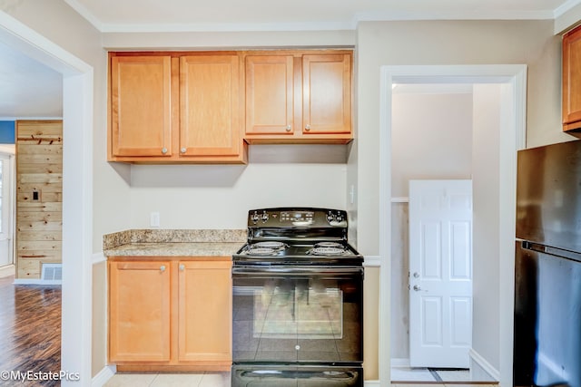 kitchen with light tile patterned floors, ornamental molding, black appliances, and wood walls