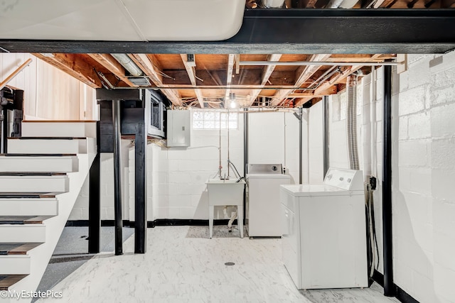 basement featuring separate washer and dryer, sink, and electric panel