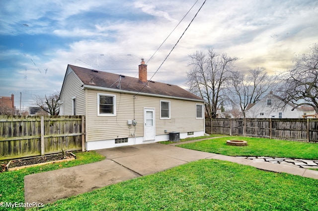 rear view of property featuring a fire pit, a lawn, central AC, and a patio