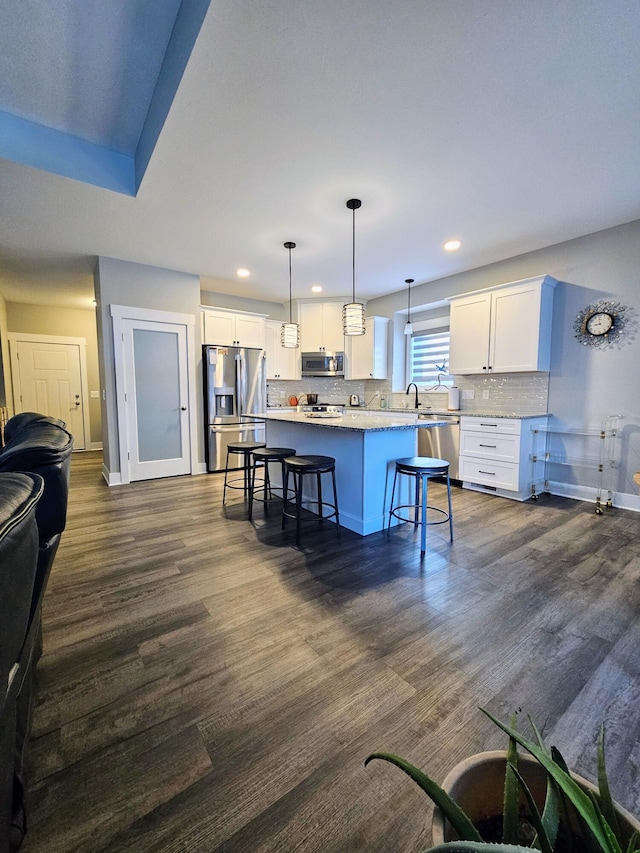 kitchen with a kitchen island, appliances with stainless steel finishes, a breakfast bar area, dark hardwood / wood-style flooring, and hanging light fixtures