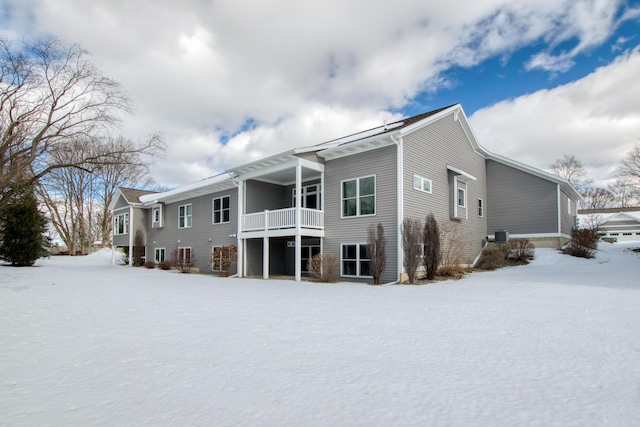 snow covered back of property featuring a balcony