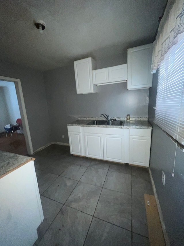 kitchen featuring white cabinets, a sink, and dark tile patterned floors