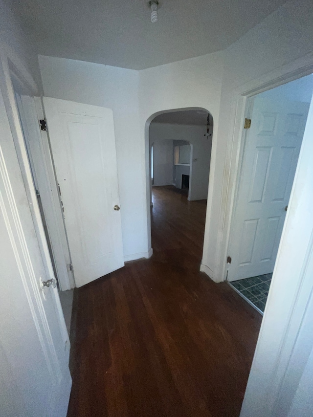 hallway featuring baseboards, arched walkways, and wood finished floors