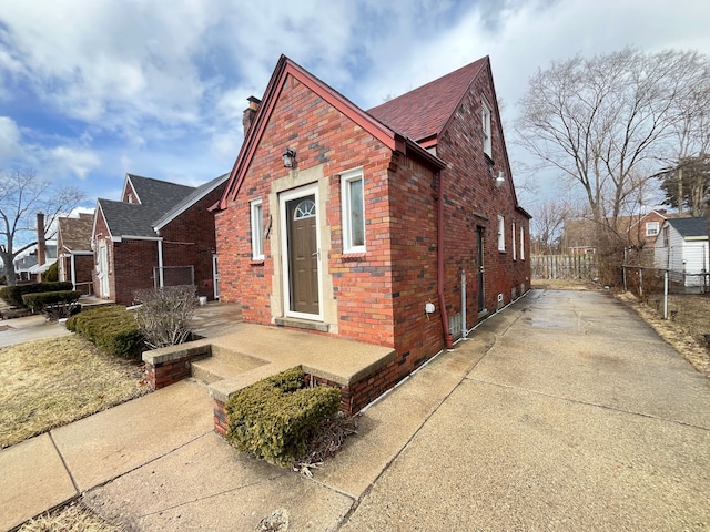 view of front of house with a chimney, fence, and brick siding