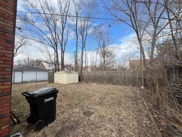 view of yard featuring a storage unit, a detached garage, fence, and an outbuilding