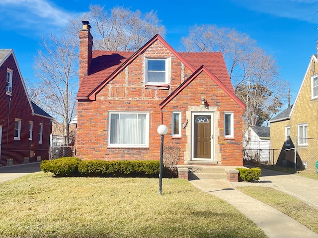 bungalow-style home with fence, brick siding, a chimney, and a front lawn