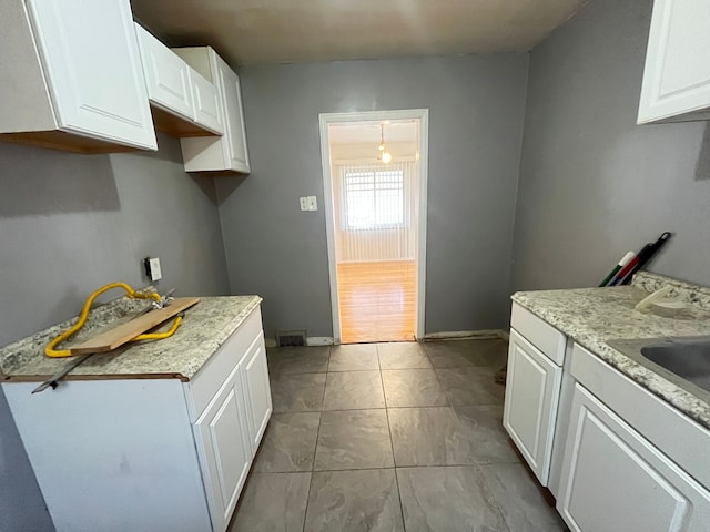 kitchen with a sink, light countertops, white cabinetry, and baseboards