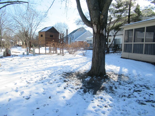 yard covered in snow with a sunroom