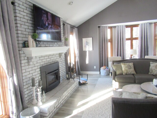 living room with lofted ceiling, a fireplace, and light wood-type flooring