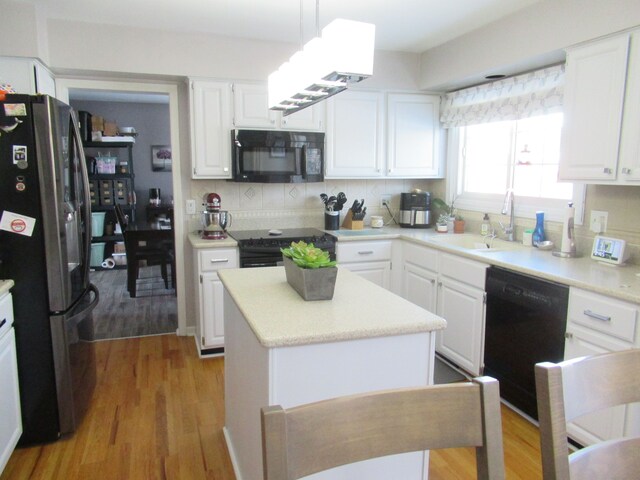 kitchen featuring hanging light fixtures, white cabinetry, a center island, and black appliances