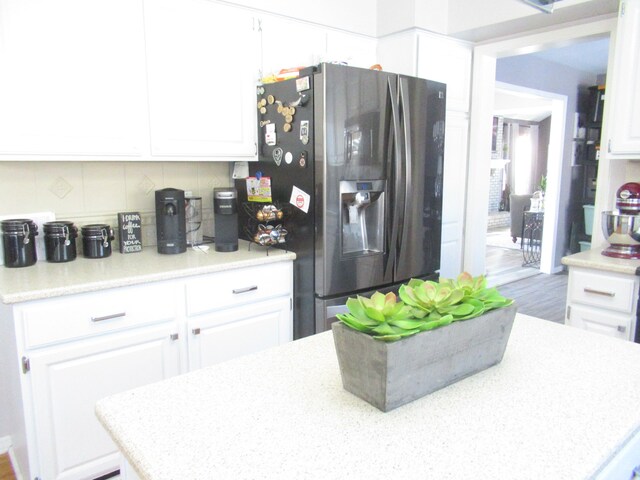 kitchen with stainless steel fridge with ice dispenser, backsplash, hardwood / wood-style floors, and white cabinets