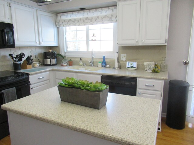 kitchen featuring sink, white cabinets, backsplash, and black appliances