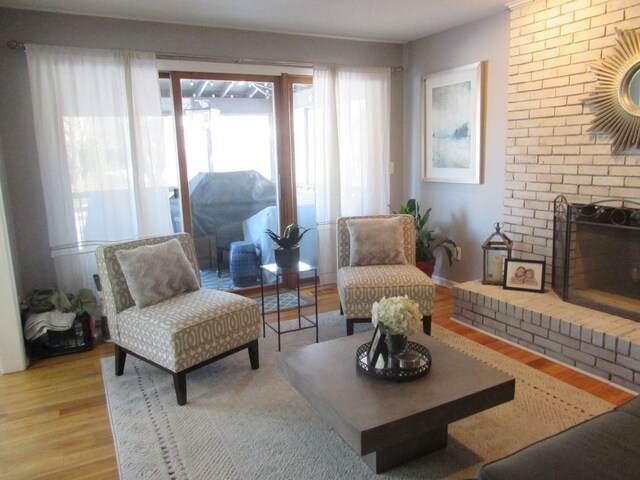 living room featuring a brick fireplace and light wood-type flooring