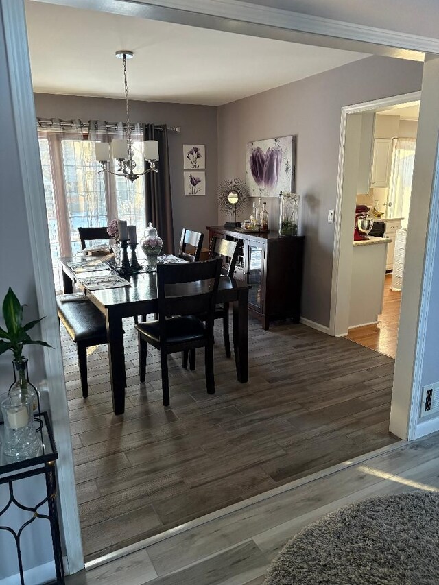 dining space featuring wood-type flooring and a notable chandelier