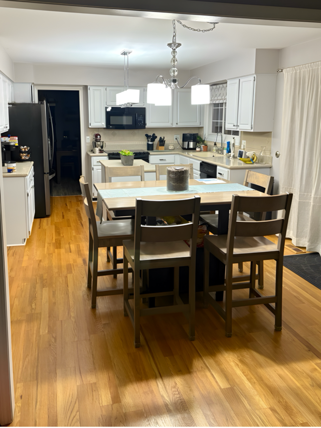 kitchen featuring white cabinets, hanging light fixtures, and black appliances