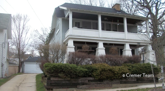 view of front of property featuring a garage, a balcony, and an outbuilding