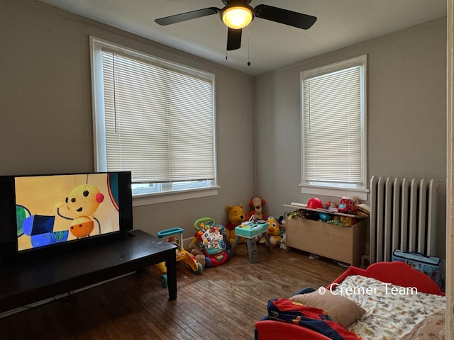 game room with wood-type flooring, radiator heating unit, and ceiling fan