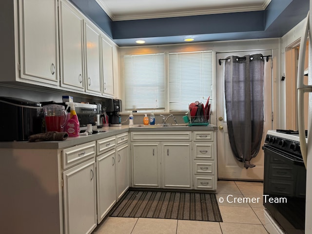 kitchen featuring white cabinets, range, sink, and light tile patterned floors