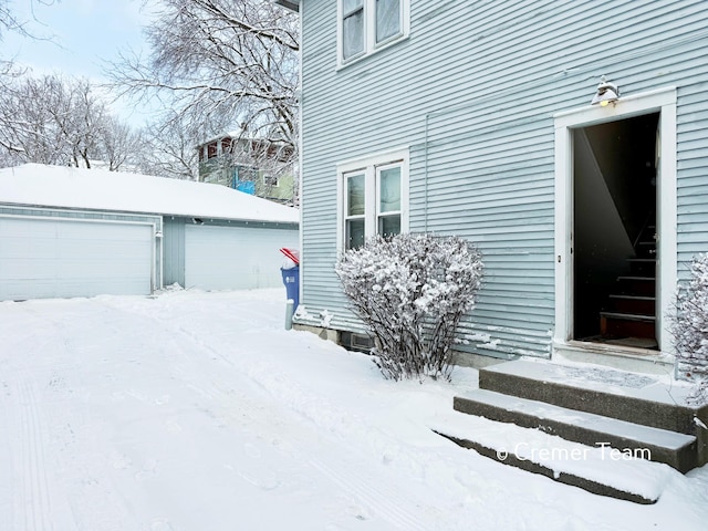 view of snow covered exterior with an outbuilding and a garage