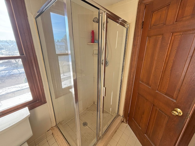 bathroom with tile patterned flooring, a shower with door, and toilet