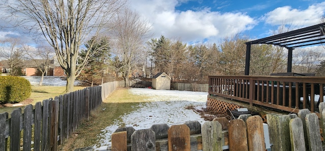 yard layered in snow with a storage unit, a pergola, and a deck