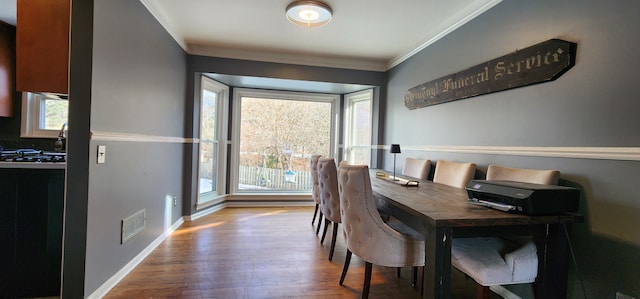 dining room featuring hardwood / wood-style floors and crown molding