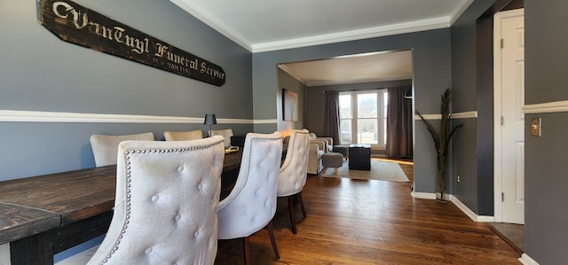 dining area featuring dark wood-type flooring and ornamental molding