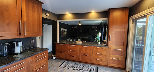 kitchen featuring dark stone countertops, a fireplace, and ceiling fan