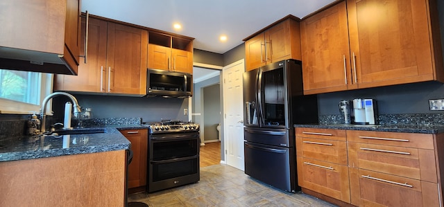 kitchen with appliances with stainless steel finishes, sink, and dark stone counters