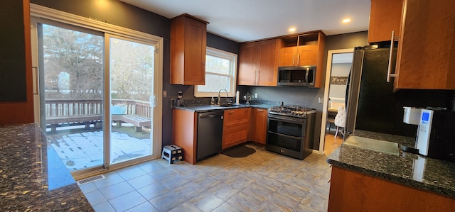 kitchen with dark stone countertops, sink, and stainless steel appliances