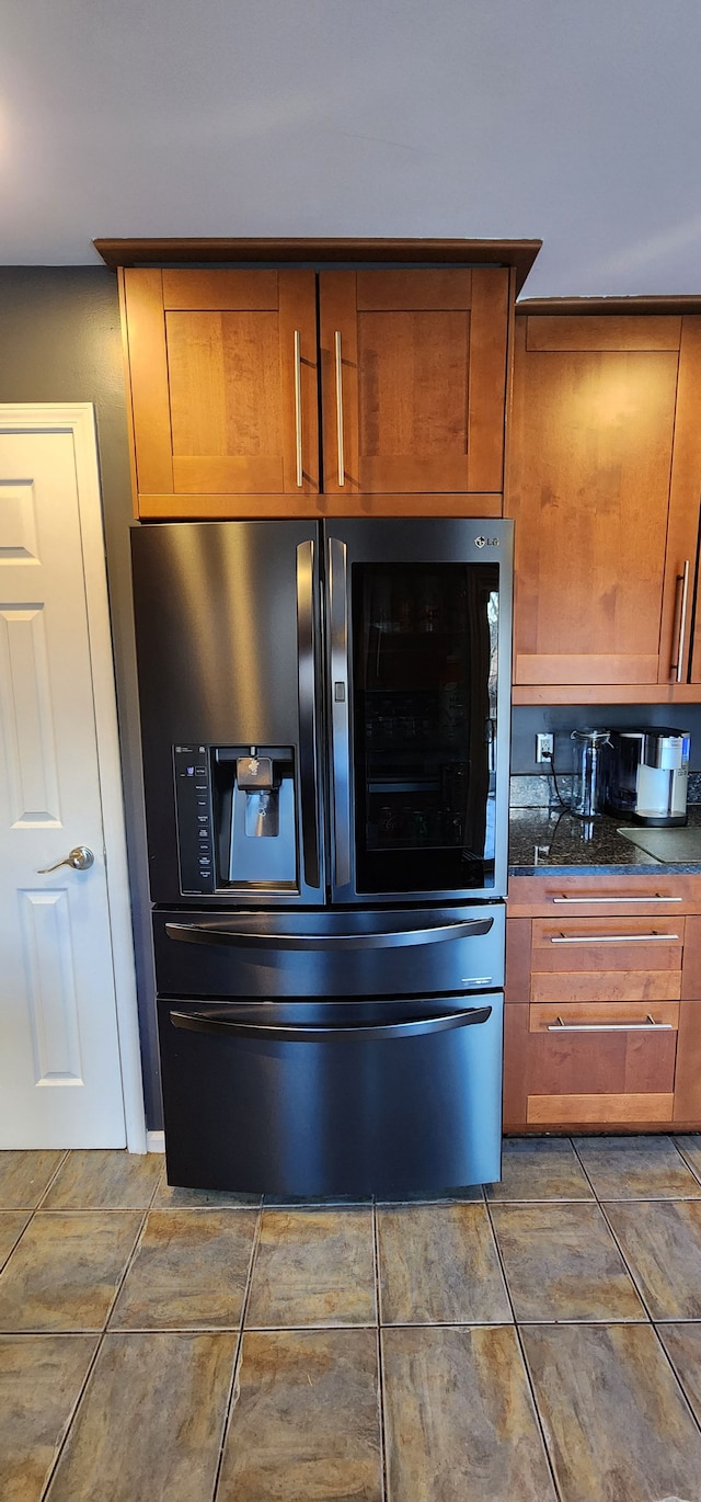 kitchen featuring dark tile patterned flooring and stainless steel fridge